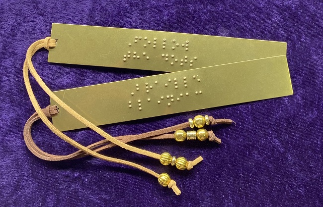 Photo of two brass braille-embossed bookmarks, each with a tan leather cord decorated with brass beads.