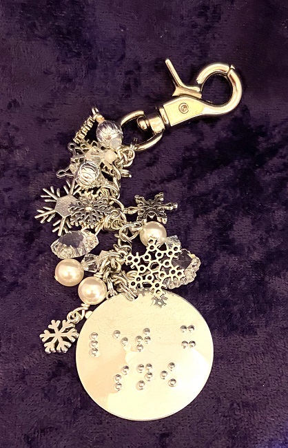 Photo of the Sparkling Snowfall Purse Charm on a purple background.